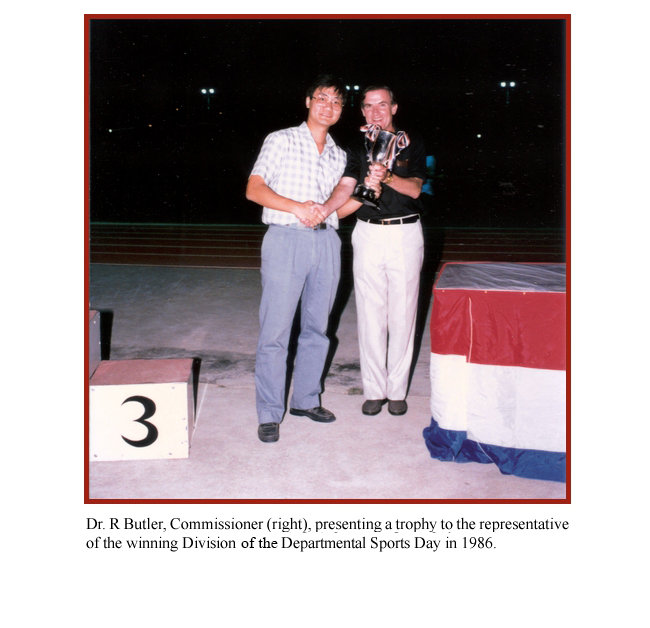 Dr. R Butler, Commissioner (right), presenting a trophy to the representative of the winning Division of the Departmental Sports Day in 1986.